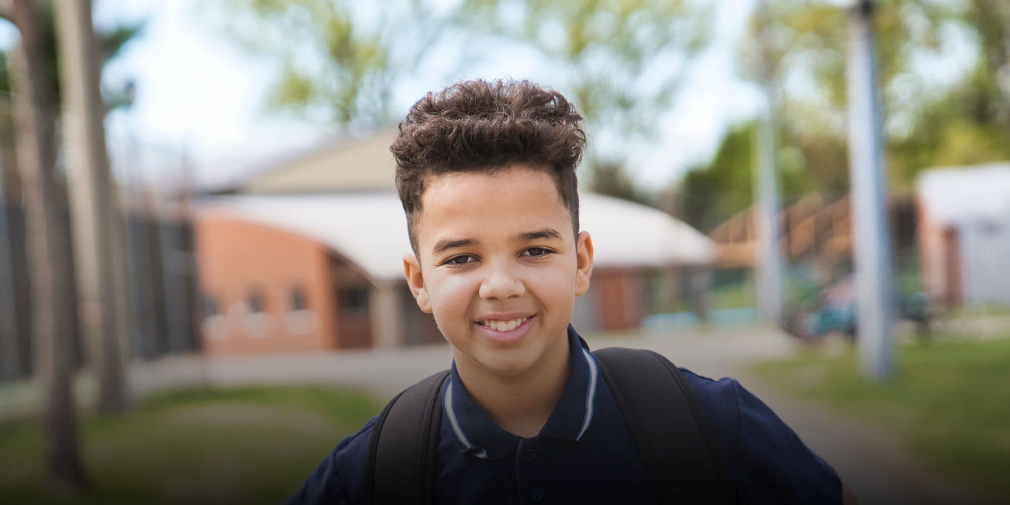 Smiling student wearing a backpack outdoors.