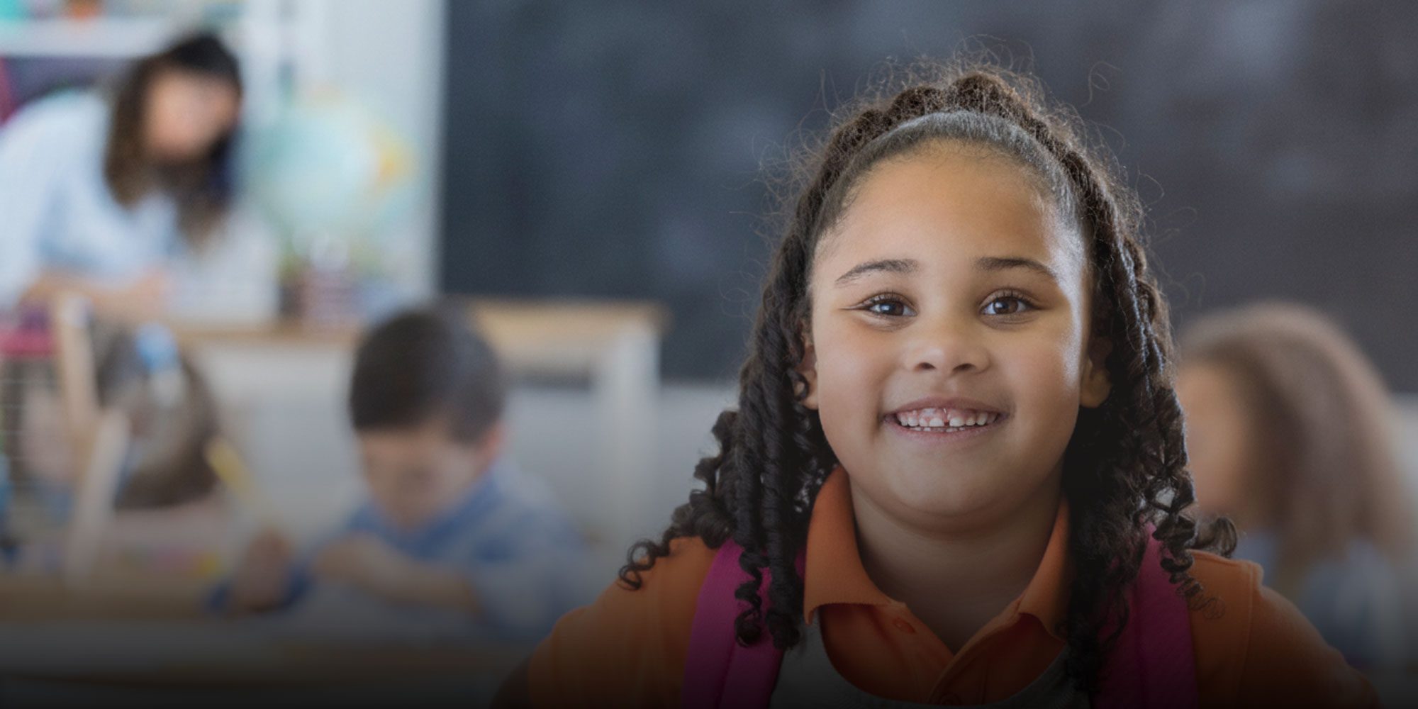 Smiling student with backpack standing in classroom